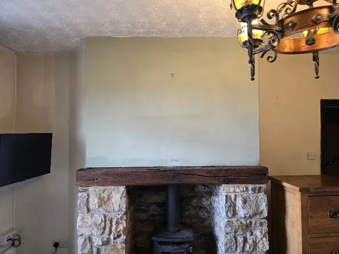 A chimney breast above a stone fireplace before decorating