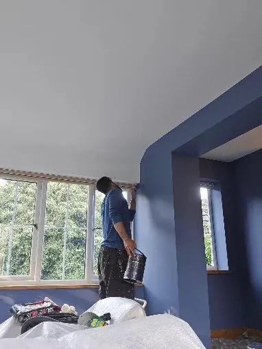 Decorator cutting in a ceiling against midnight blue walls